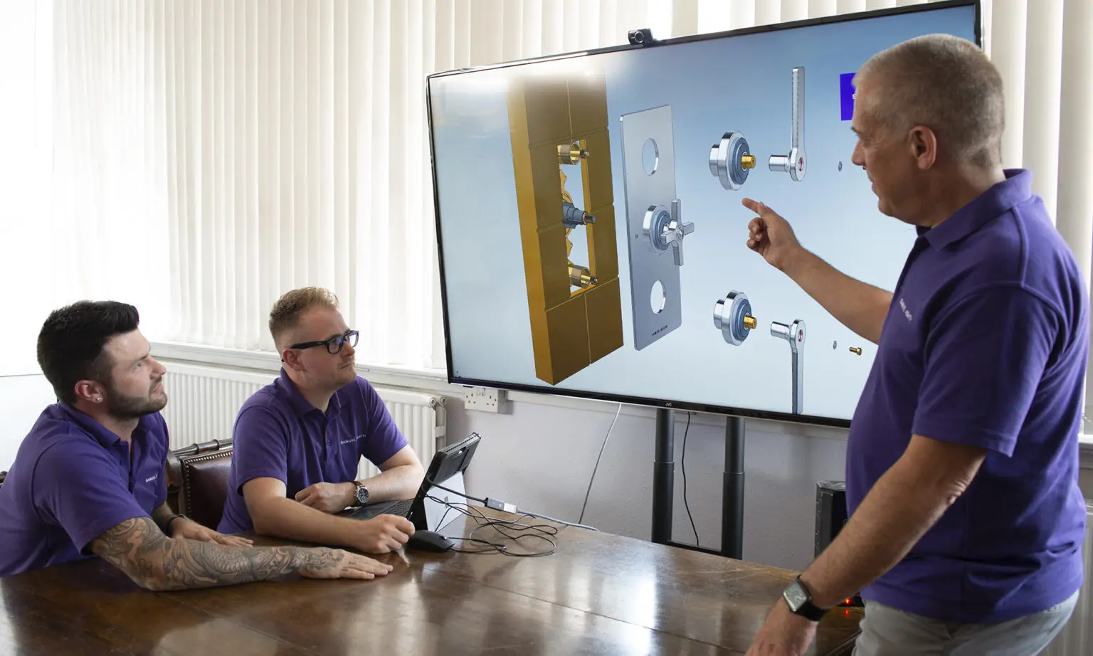 Assembly department manager presents brass prototype instructions to design engineers.