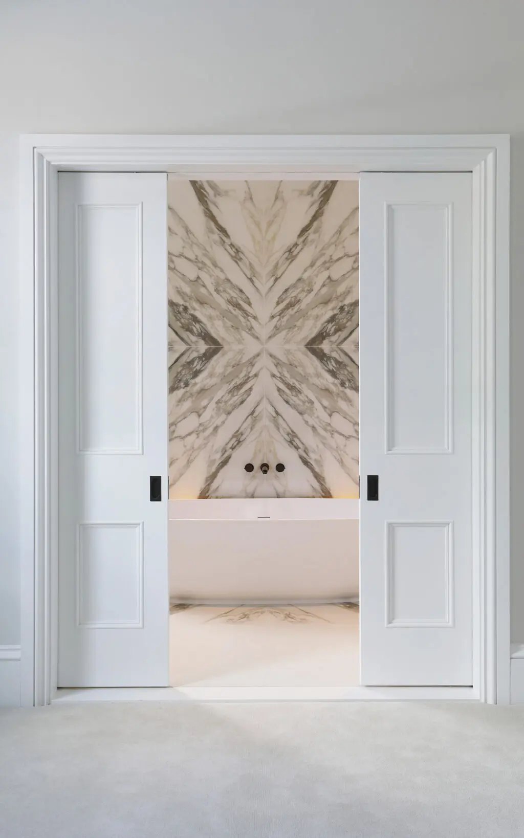 Door opening to show Samuel Heath bath tap and bookmatched marble