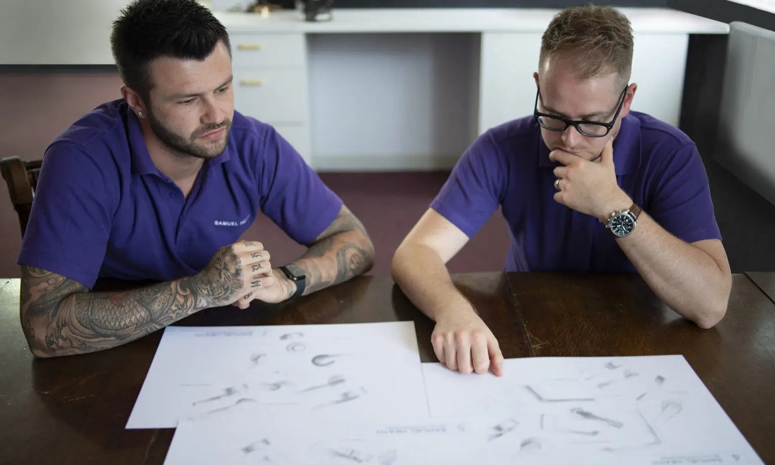 Two design engineers inspect sketches supplied by the product designer.