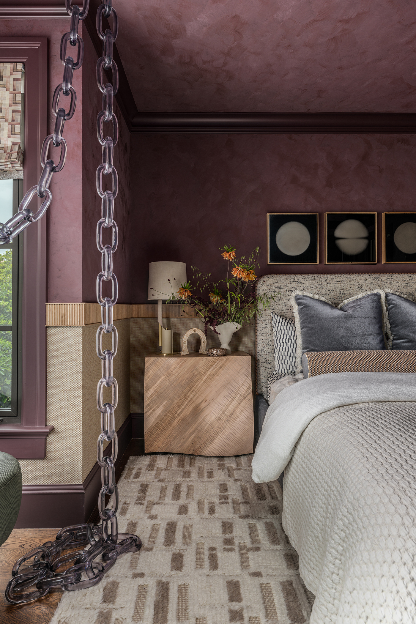 Side of bed view in The Global Nest bedroom with burgundy colour-drenched walls