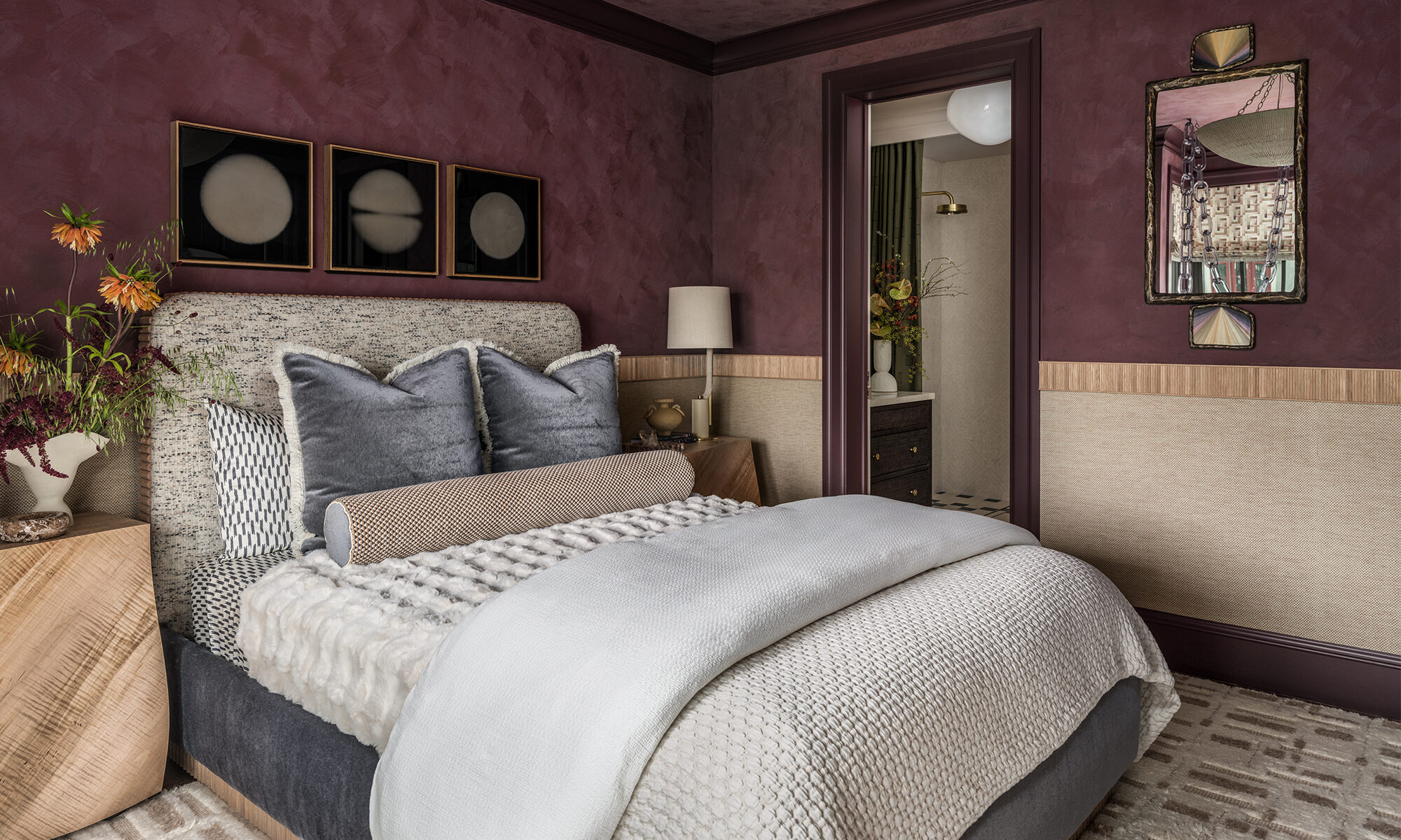 Side of bed view in The Global Nest bedroom showing tactile furnishings, facing ensuite doorway